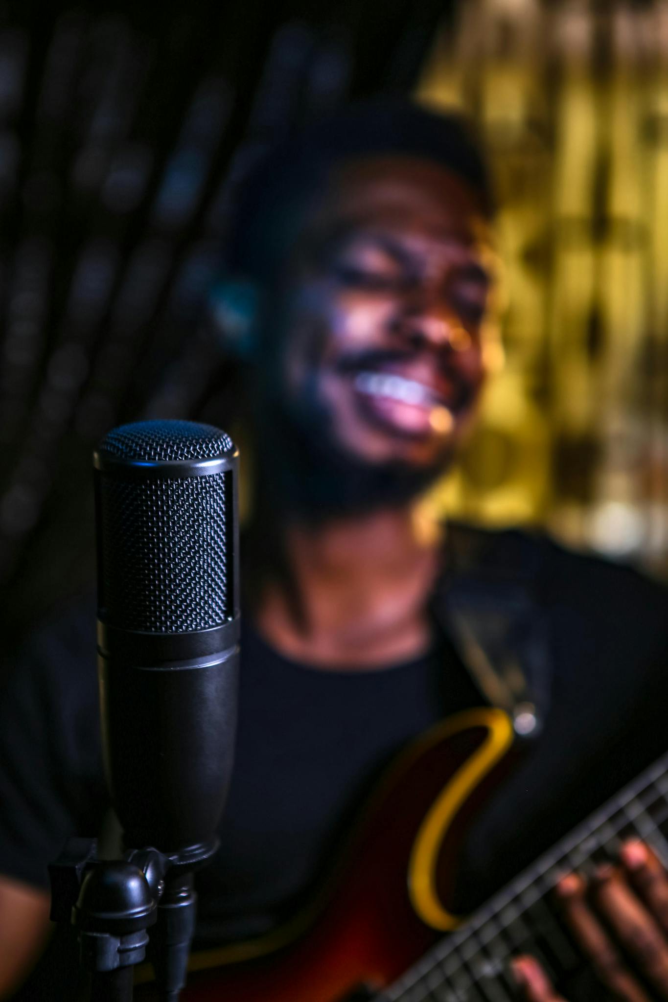 Blurred male singer playing guitar with a microphone in focus.