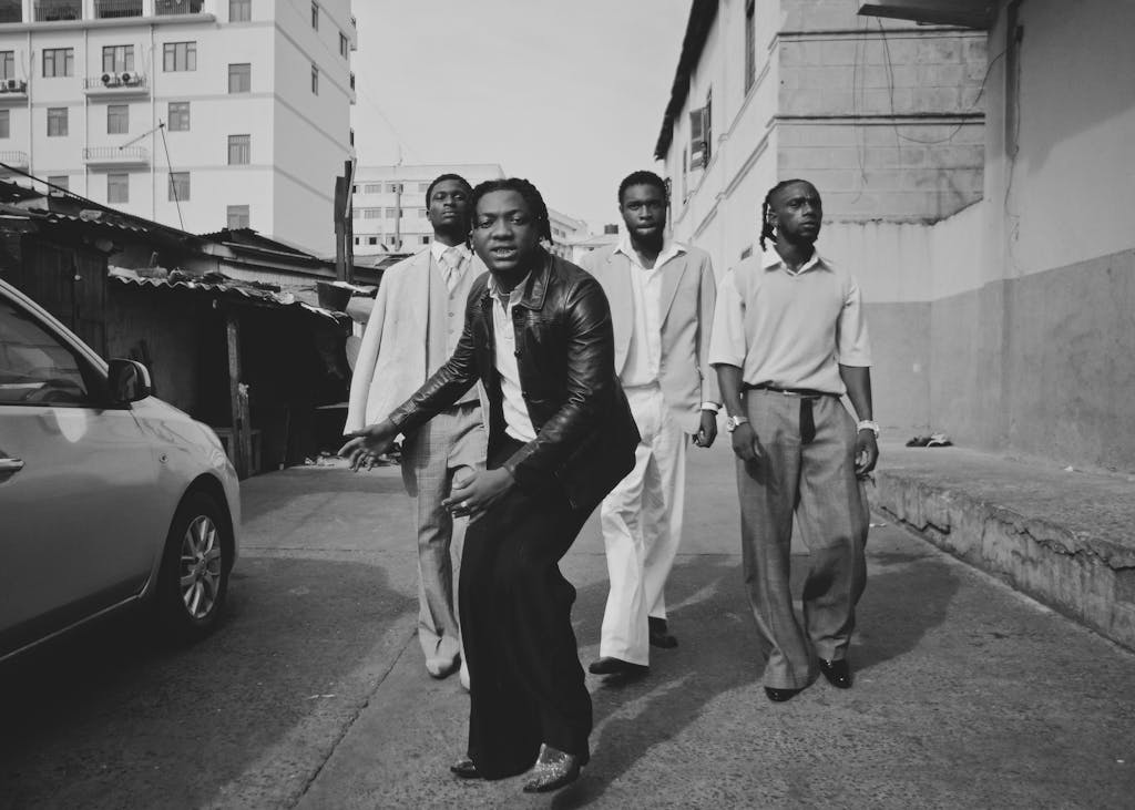 Four men in suits walk confidently on the street, exuding modern style.